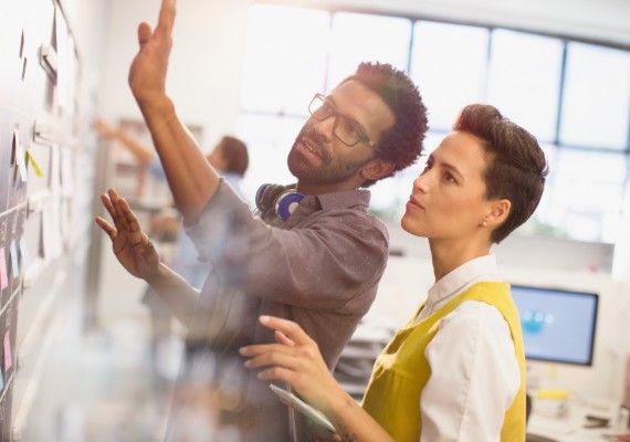 Man and woman discussing content on a whiteboard